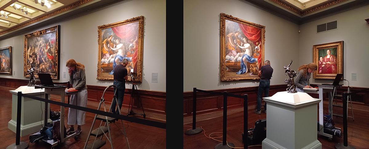Two scientists analyze a massive painting with some gear set up in a gallery