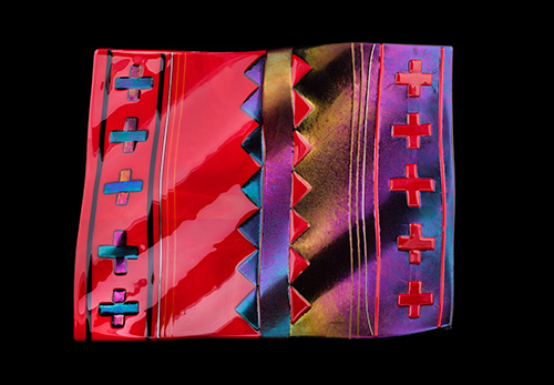 A red and purple blanket made from glass, featuring crosses and arrows