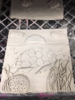 clay tile of a sea turtle swimming through coral