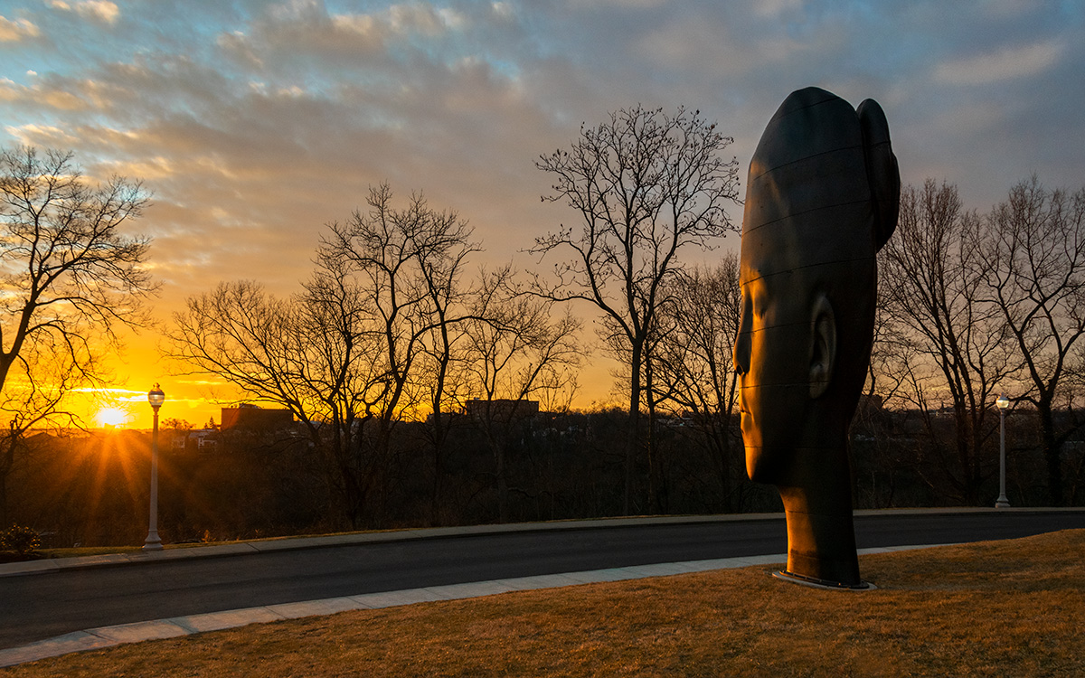 Sculpture of a girl looking out toward a sunset