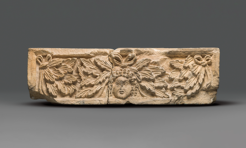 An ornately carved stone lintel with a face and jagged leaves
