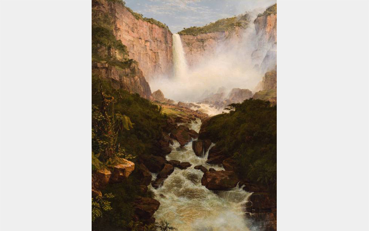 Waterfall spilling into a canyon with green vegetation