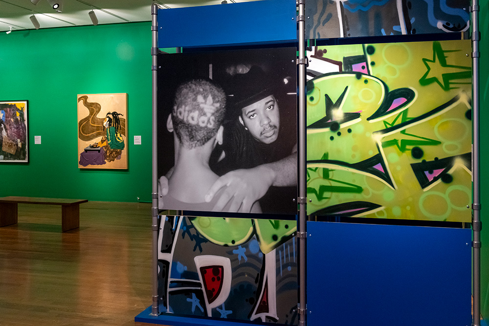 A wall featuring a photo of Run DMC and green and gray graffiti