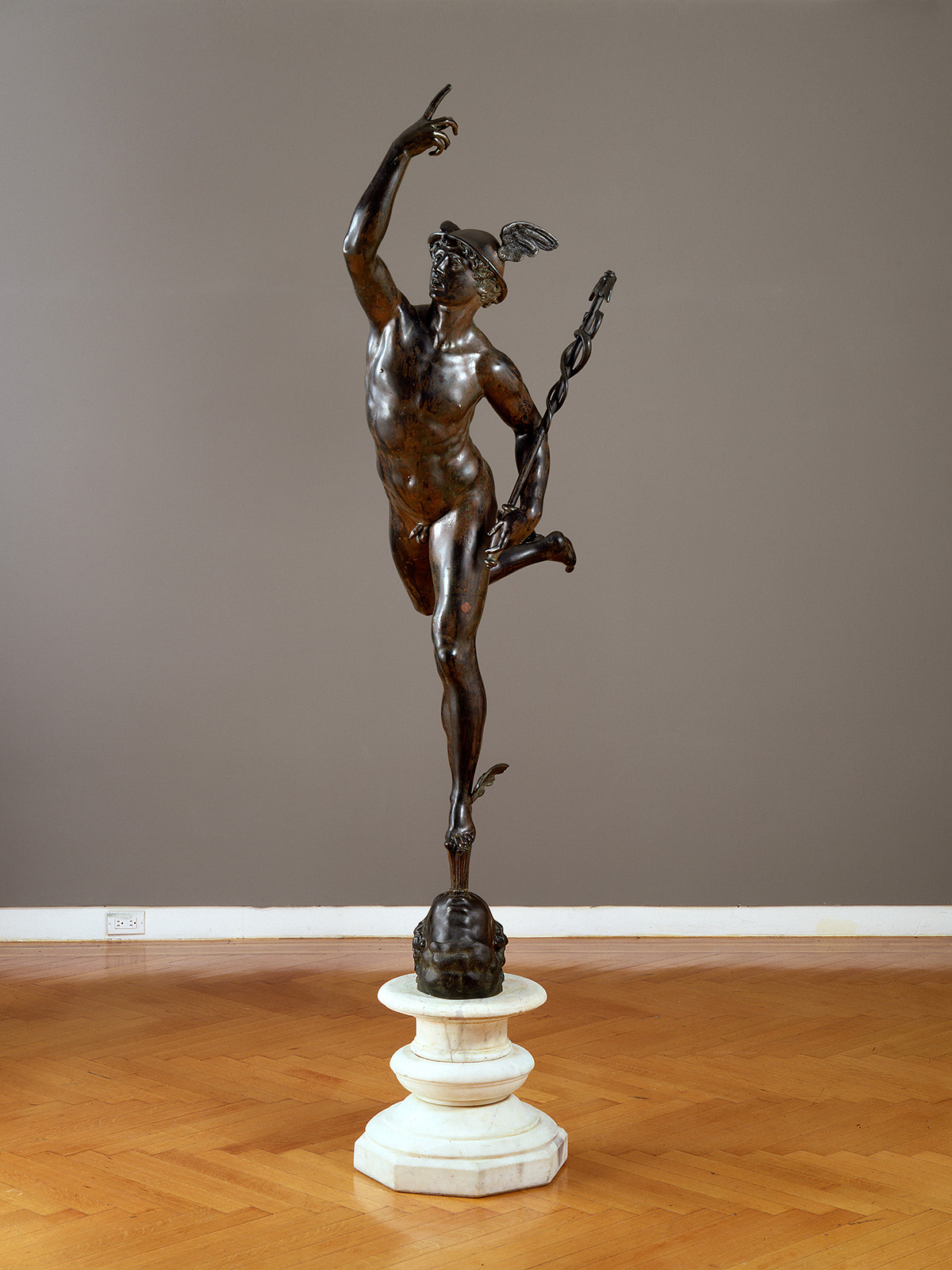 A bronze sculpture of a nude man standing on one foot
