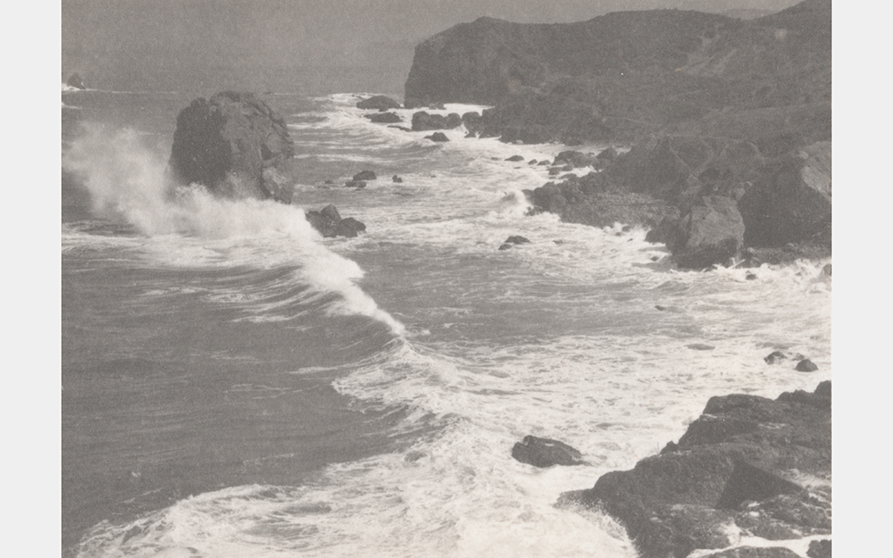 A black and white photo of waves crashing on a rocky shore