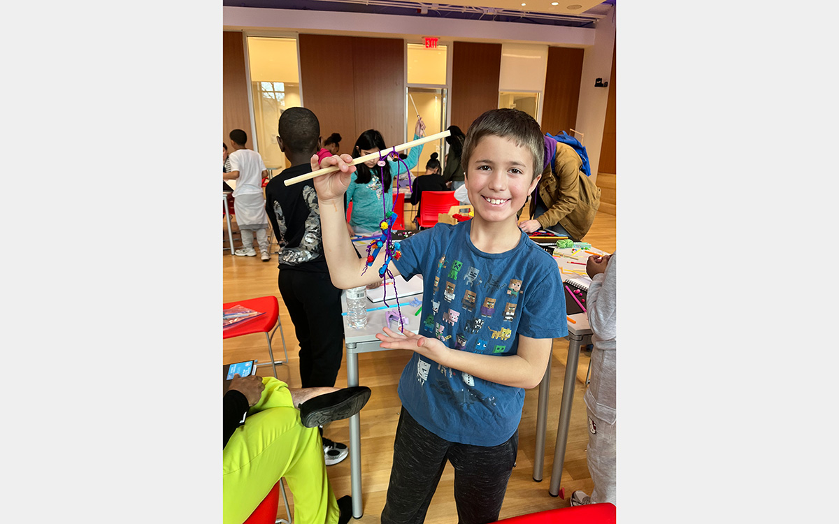 Boy with handmade mobile sculpture in a classroom