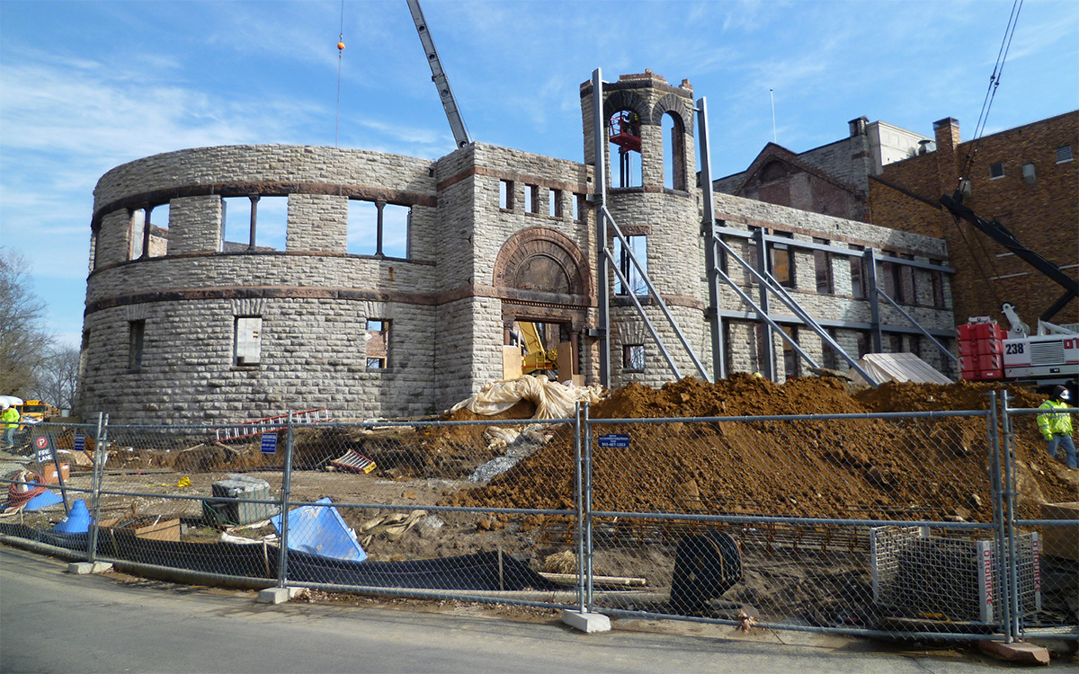 Stone walls of a gutted building surrounded by a construction site.