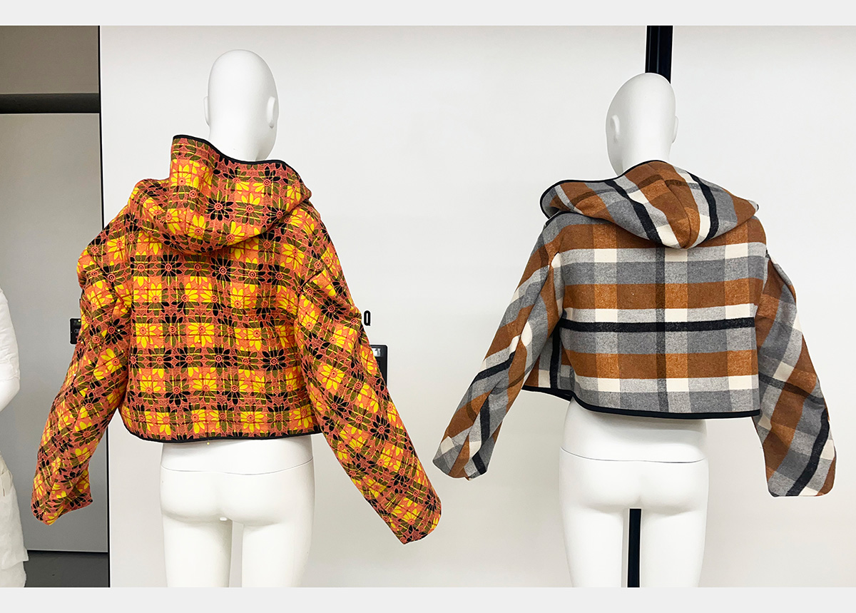 The back of the two hooded jackets on plain white mannequins. The hoods are down.