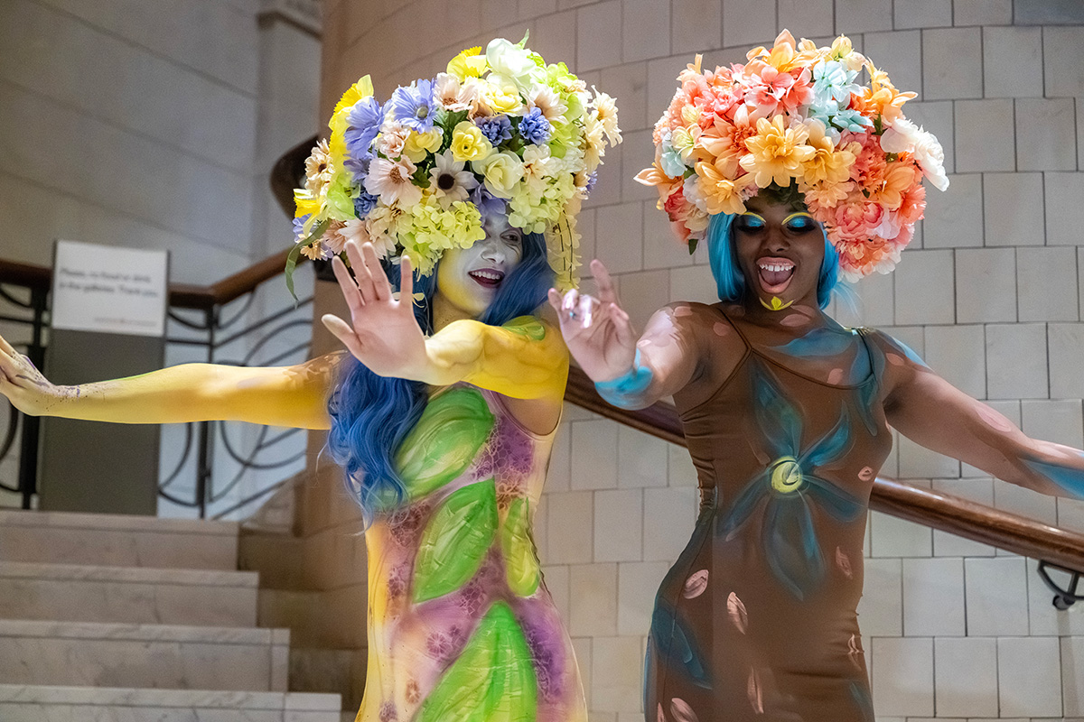 Two women with floral headdresses dance in the Great Hall