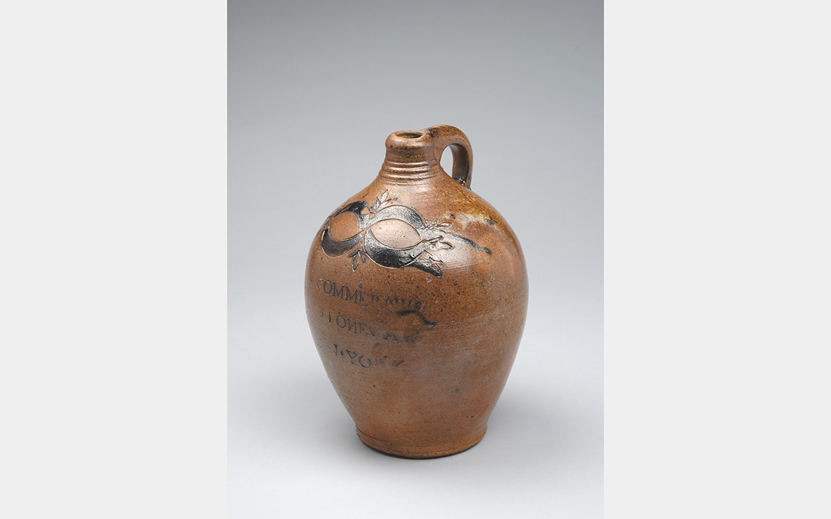 Brown ceramic jug with black decorative markings and inscription