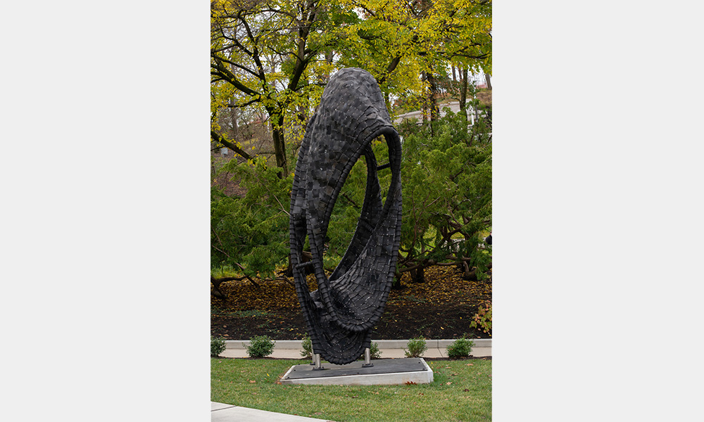 A large, black oval, covered in layered squares wrapped around the form