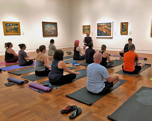 Visitors sit on yoga maps in a gallery