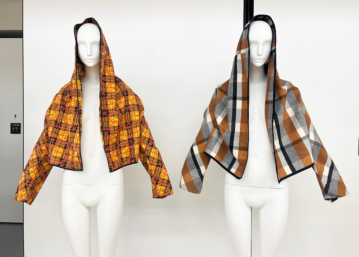 Two hooded jackets on plain white mannequins. The hoods are up.