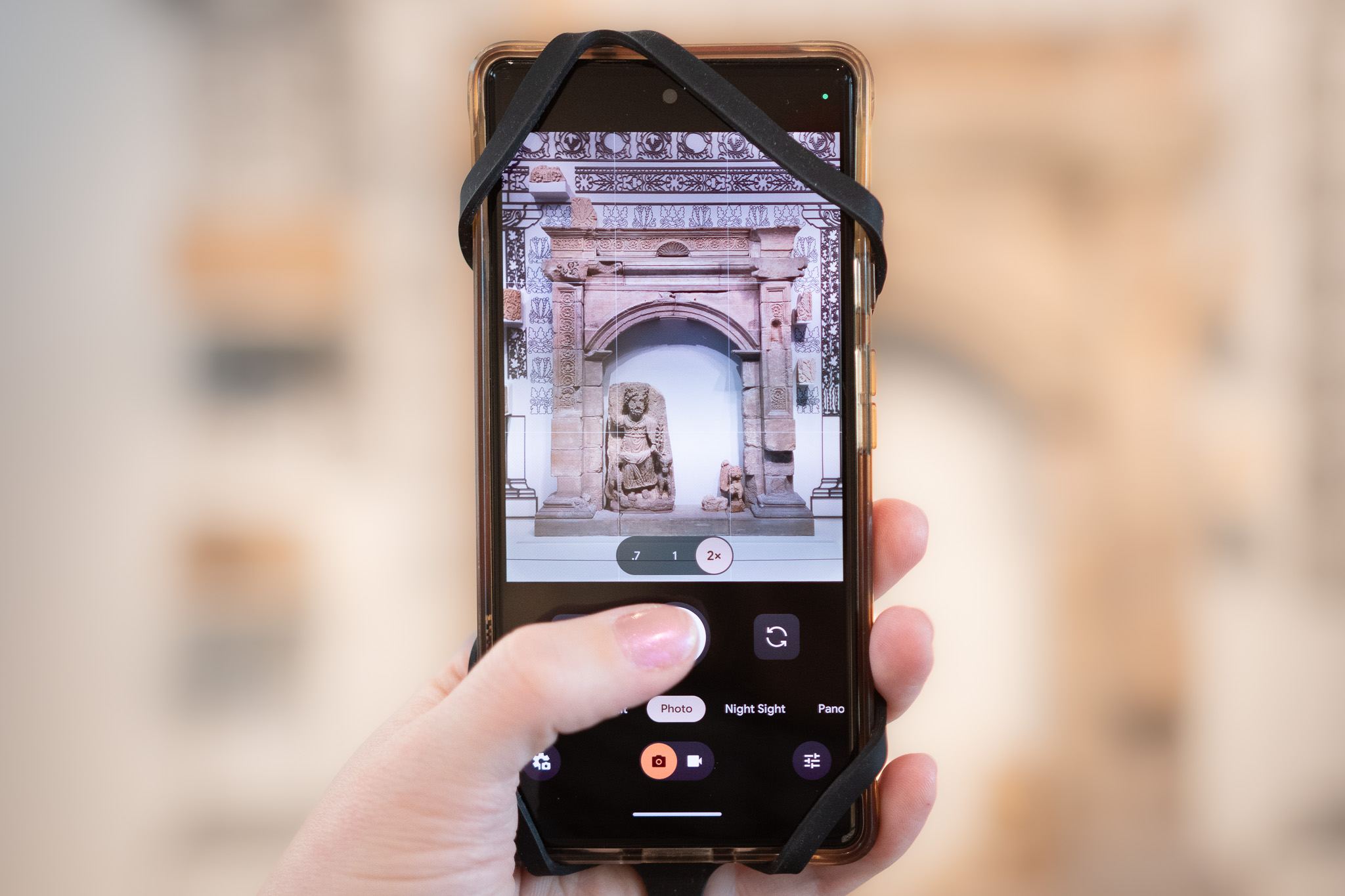 A black lanyard on a cell phone taking a picture of art