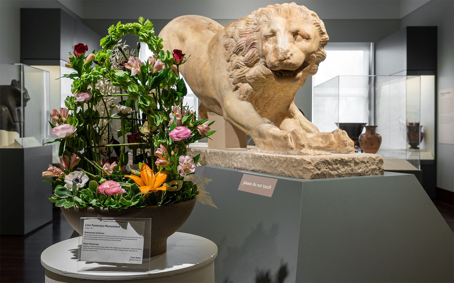 A large green floral arrangement in front of a massive sculpture of a lion
