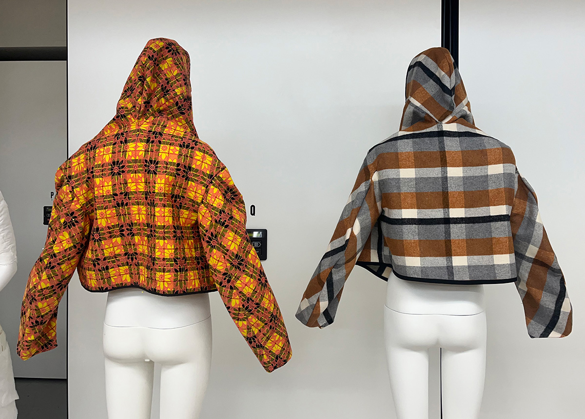 The back of the two hooded jackets with the hoods up.