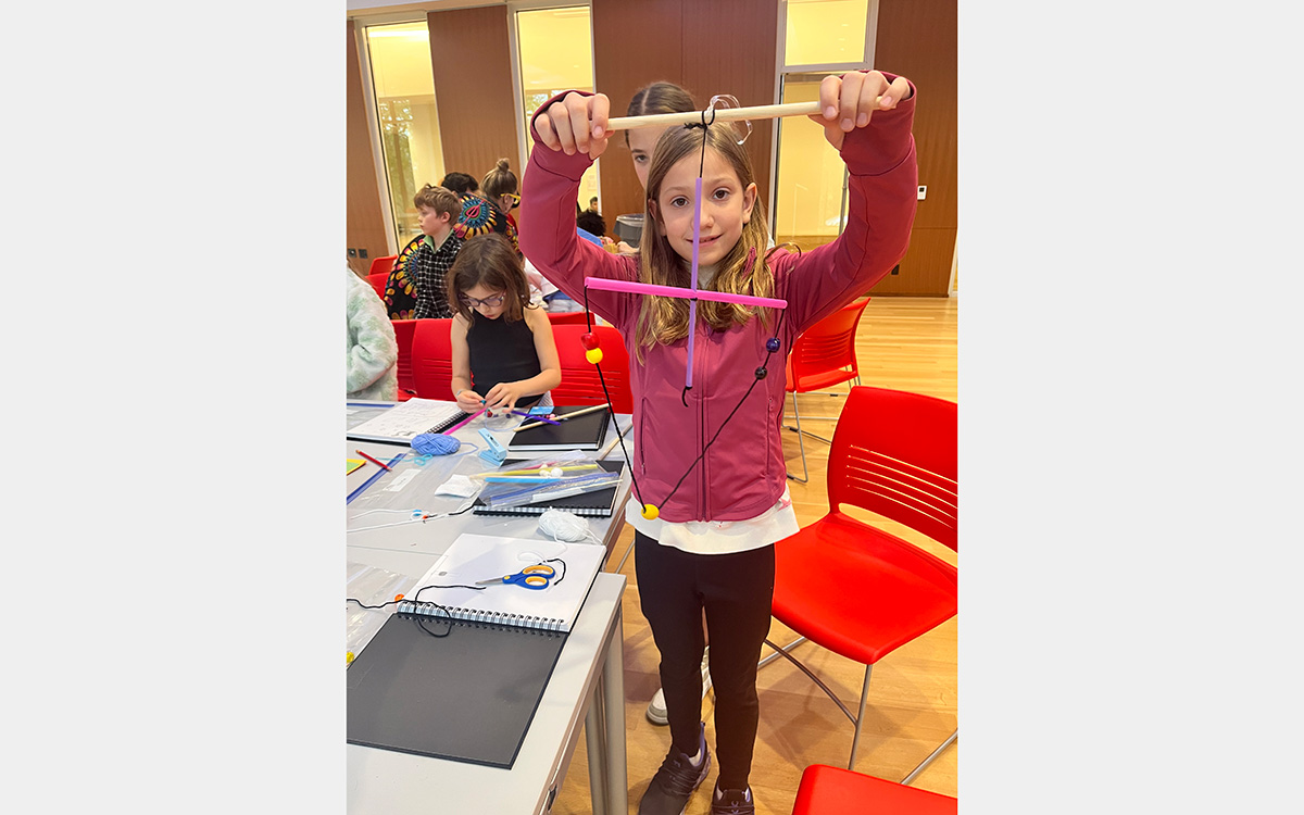 Girl with handmade mobile sculpture in a classroom