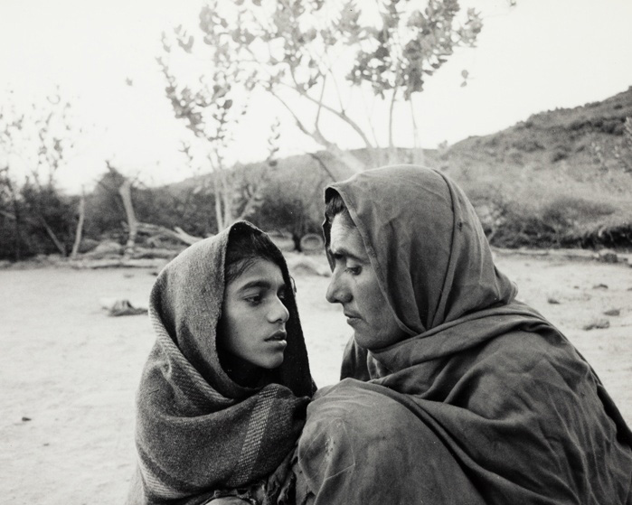 Two people wrapped in fabric look closely into each other's faces